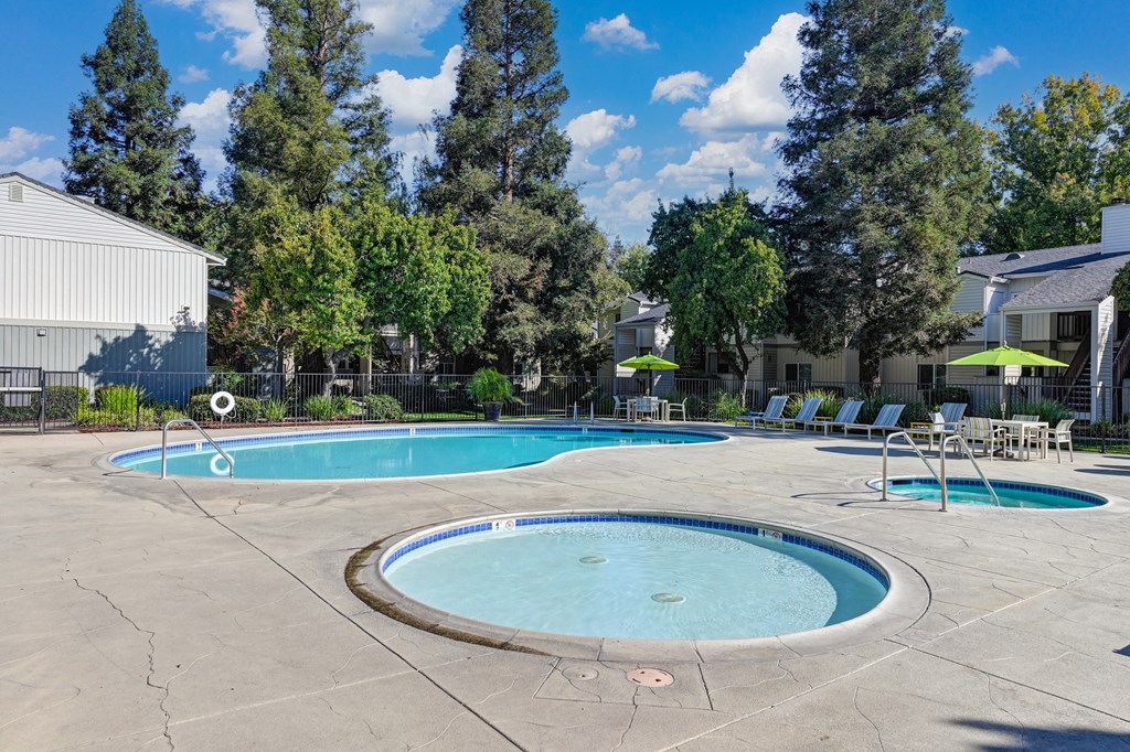 swimming pool and spa area.  There are lounge chairs and a table with umbrella in the distance. at Monte Bello Apartments, California