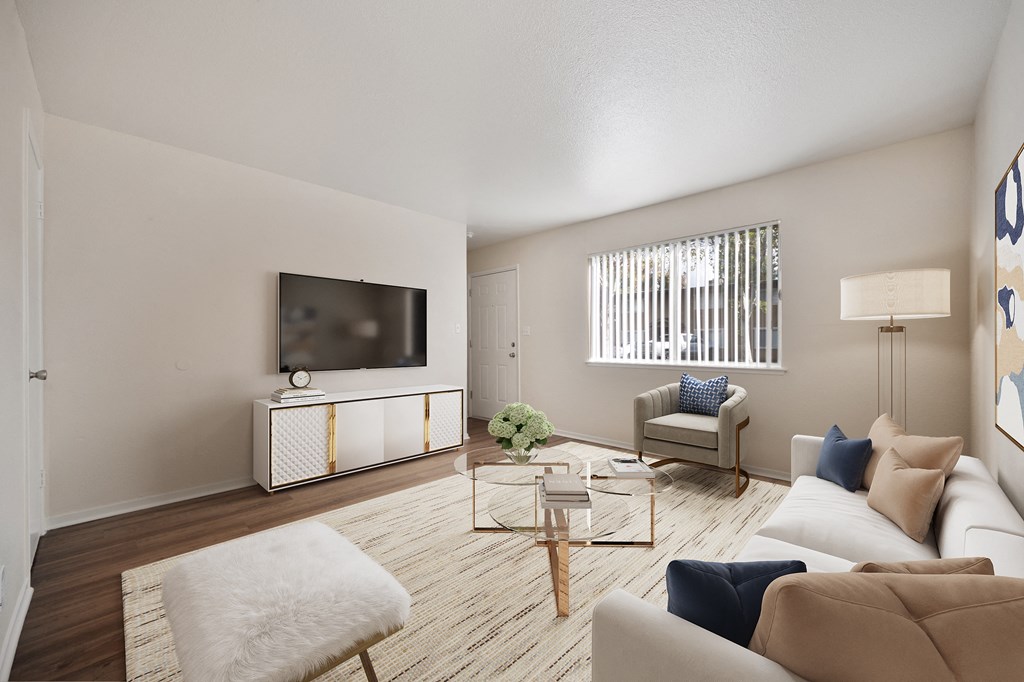 A living room with a white sofa, a white chair, a wooden coffee table, and a television on a cabinet.