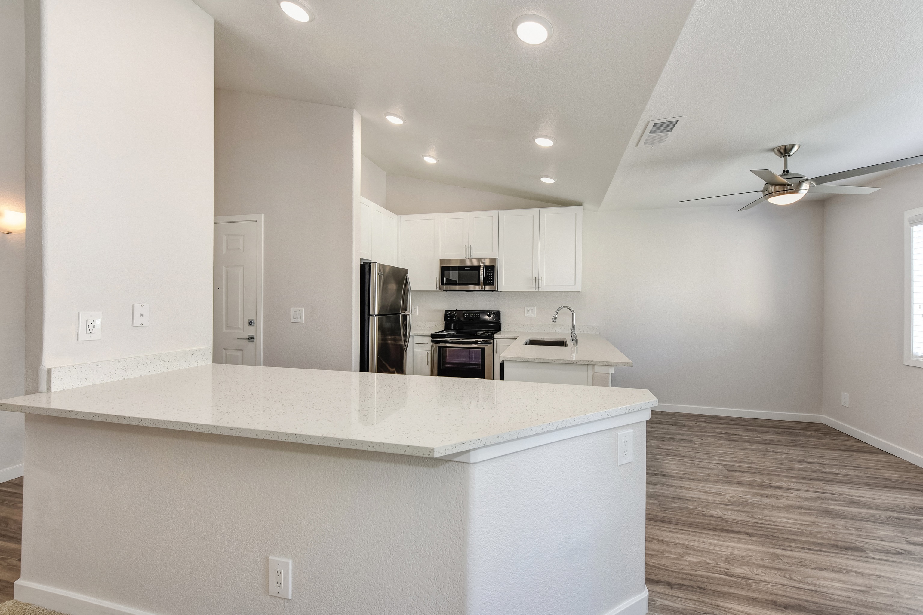 White Kitche with Hardwood Inspired Floor, White Counter and Ceiling Fan/Light at The Legacy Apartments, Antelope, California