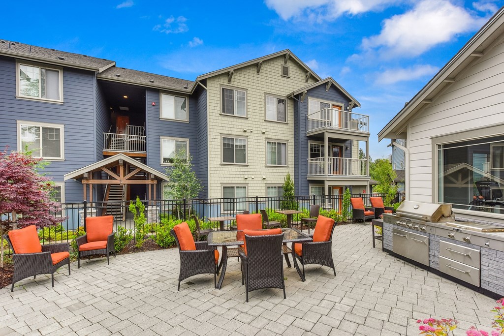 Outdoor Seating Area with Grill, Orange Chairs, Tile Inspired Floor, Blue Apartment Exterior