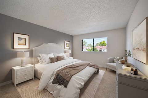 A well-lit bedroom with a large bed and a window showing a view of the outdoors.