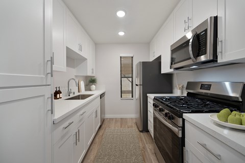 A modern kitchen with white cabinets and stainless steel appliances.