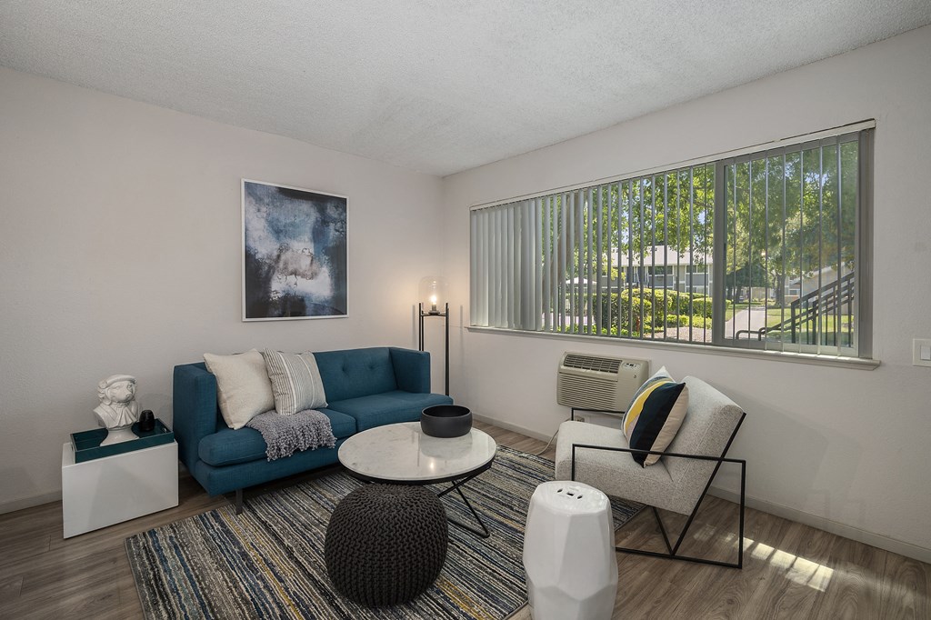 a living room with a blue couch and two chairs at Pinecrest Apartments, Davis ,95616
