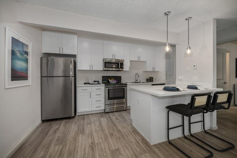 an open kitchen and dining area with stainless steel appliances and white cabinets