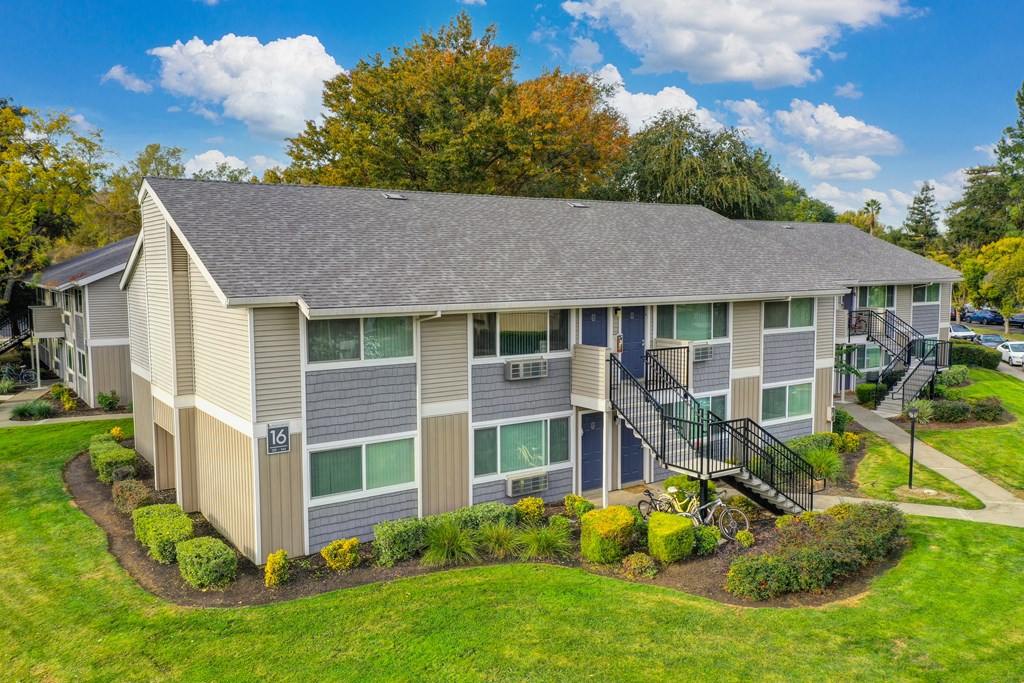Elevated drone shot of the Pinecrest exterior community and two story building with pretty blue front doors. at Pinecrest Apartments, Davis, California