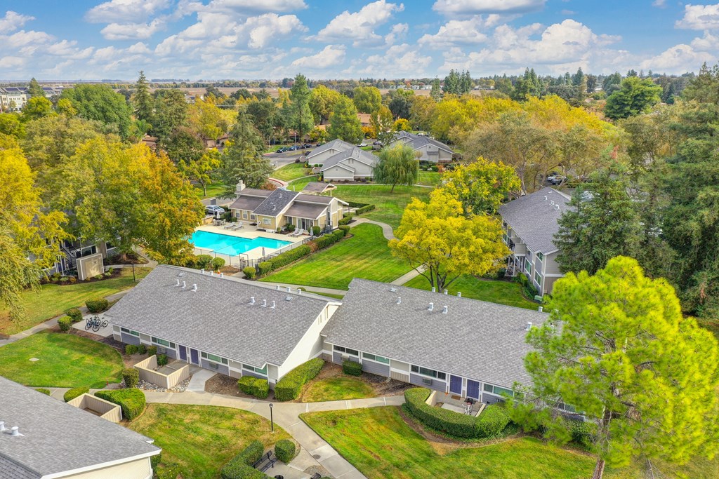 Elevated drone shot of the Pinecrest exterior community. Single story buildings with the blue swimming pool area in the distance. at Pinecrest Apartments, California