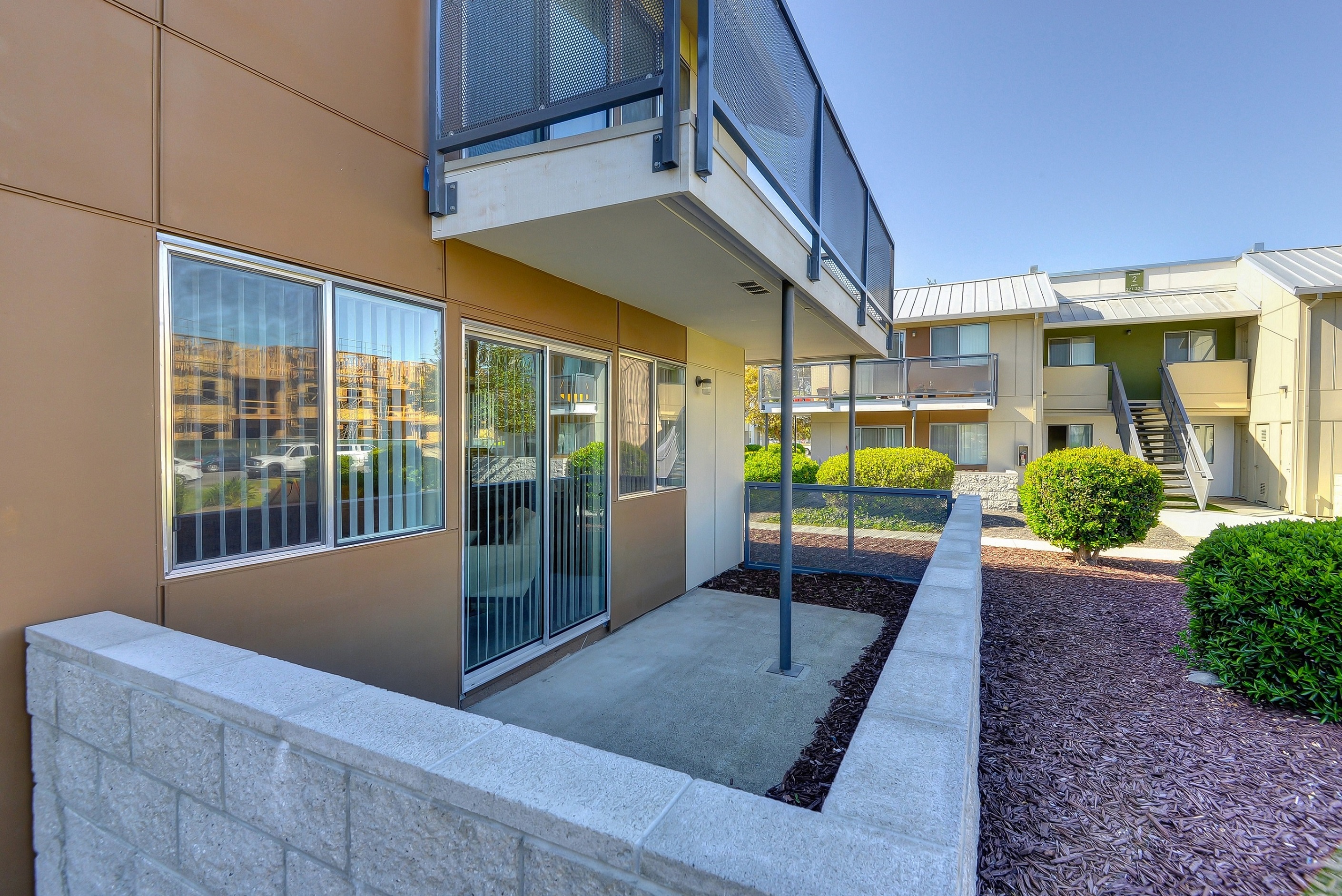 Private Patio with Porch, Wood Chip Floor, Bushes, and Open Blind Windows at Addison Ranch Apartments, California