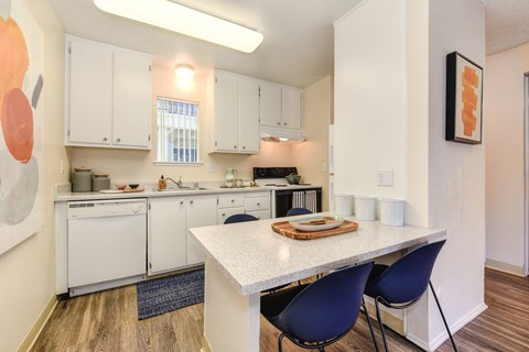 a kitchen with white cabinets and a white counter top and a table with blue chairs