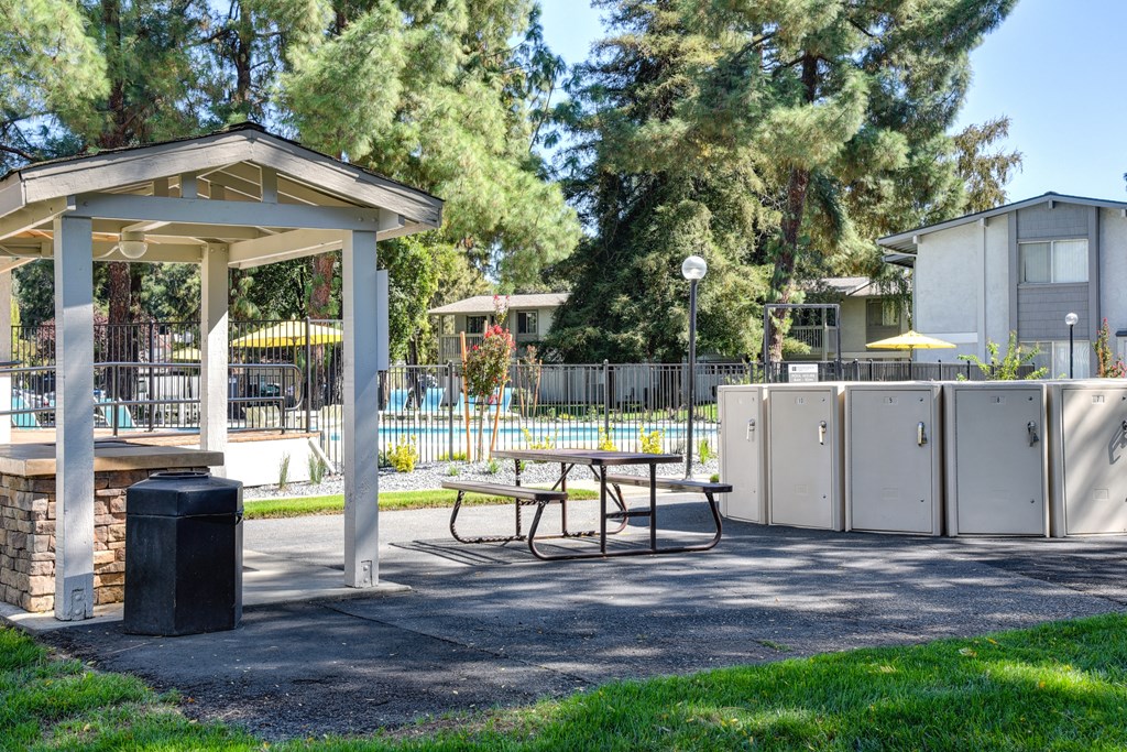 Community BBQ area with a picnic table and a trash can at Renaissance Park Apartments, Davis ,36305