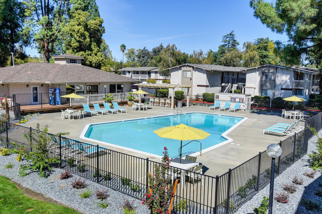 Swimming pool area which is fenced and multiple lounging options around the pool deck. at Renaissance Park Apartments, California