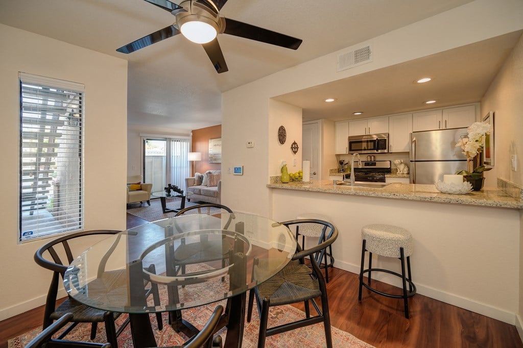 Model home dining area with ceiling fan. Open floor plan feel since you can view kitchen and living room from the dinning area. Dining table is set for four at Rocklin Manor  Apartments, Rocklin