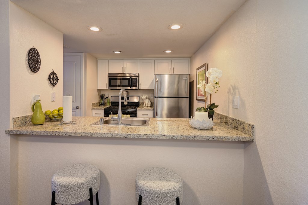 Kitchen Bar Seating with White Bar Stools, Granite Countertop, Sink, Refrigerator and Microwave at Rocklin Manor  Apartments, Rocklin  , California