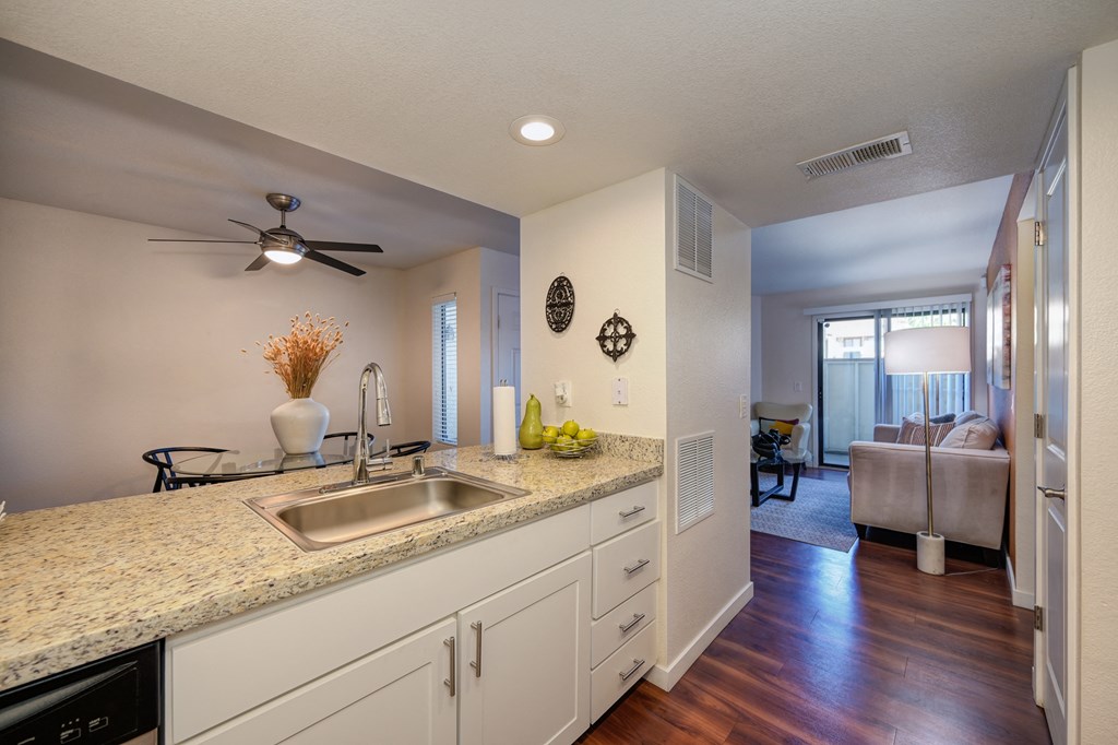 Model kitchen with hard wood inspired flooring, white counters, ceiling fan in dining area and views of the living room at Rocklin Manor  Apartments, Rocklin  , CA