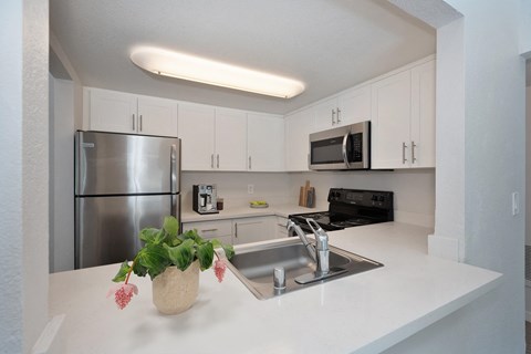 a kitchen with white counter tops and a stainless steel refrigerator