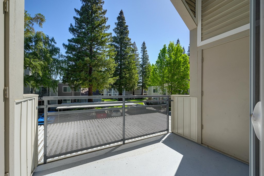the view of a tennis court from a balcony with a fence at Rush River Apartments, Sacramento