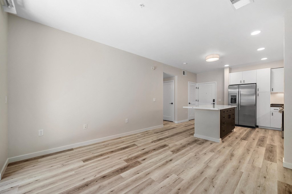 an empty living room with a kitchen and a stainless steel refrigerator at Sierra Gateway Apartments, Rocklin