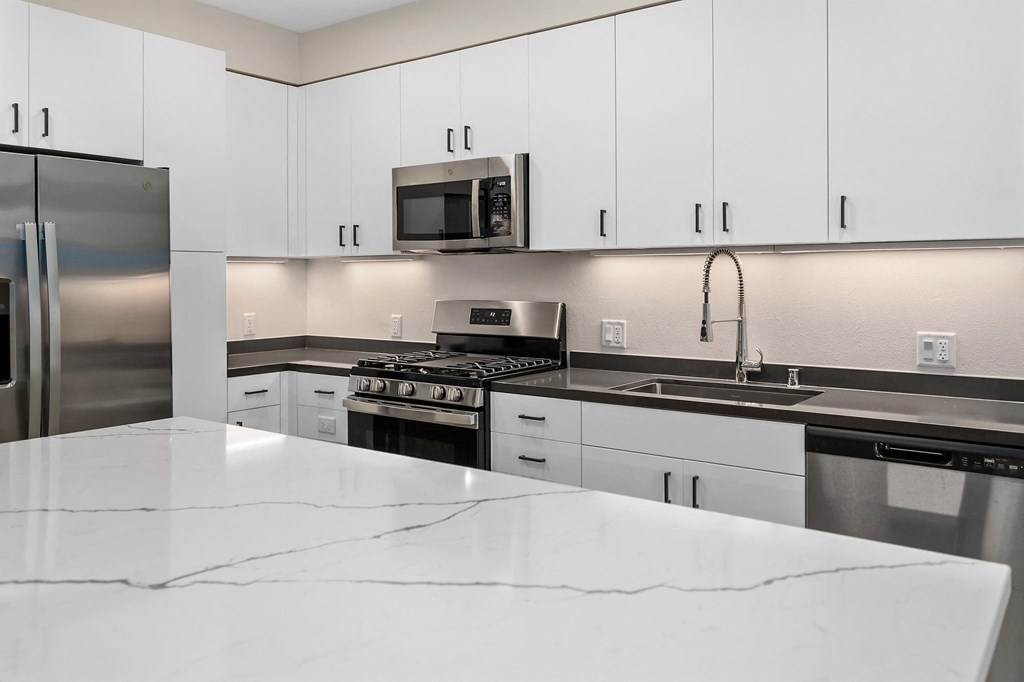 an all white kitchen with stainless steel appliances and white counter tops at Sierra Gateway Apartments, Rocklin, California