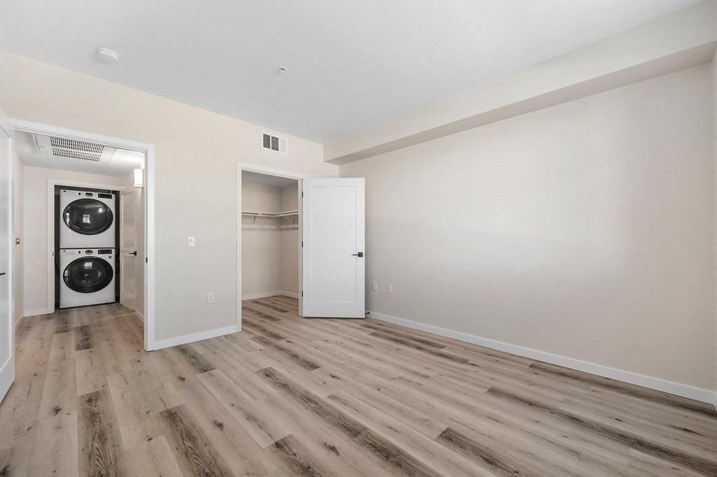a living room with white walls and wood floors and a washer and dryer at Sierra Gateway Apartments, California