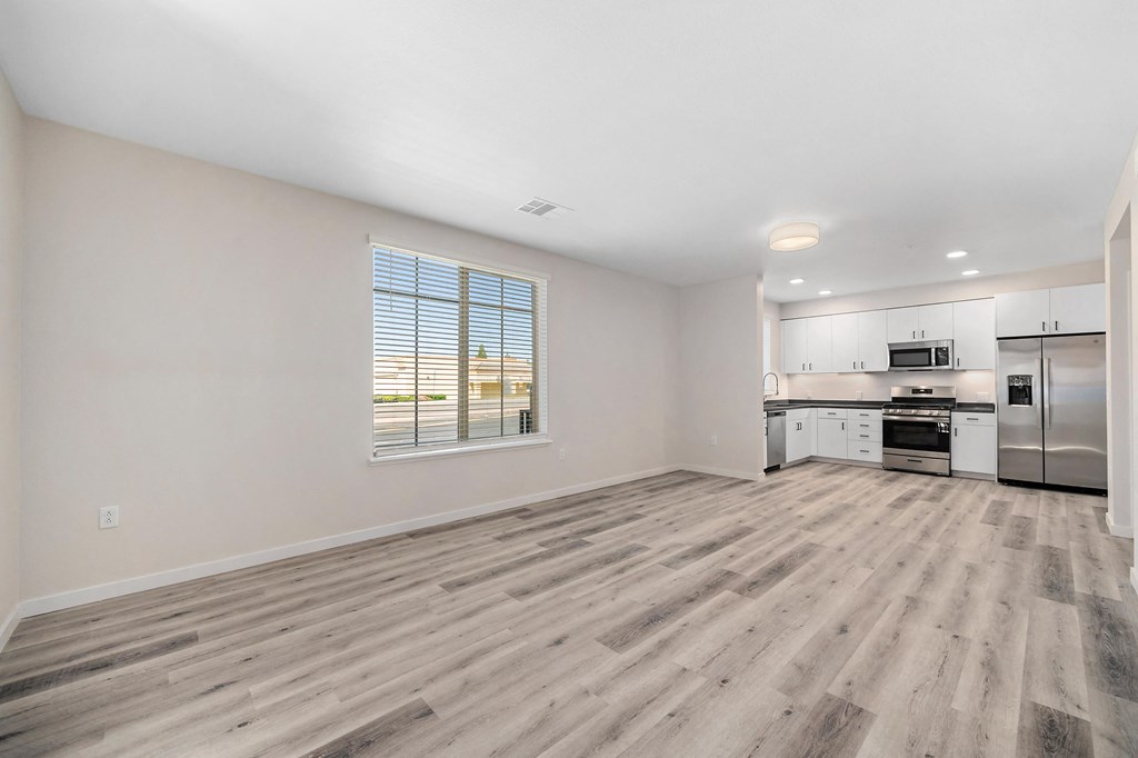 an empty living room and kitchen with wood flooring and a window at Sierra Gateway Apartments, Rocklin