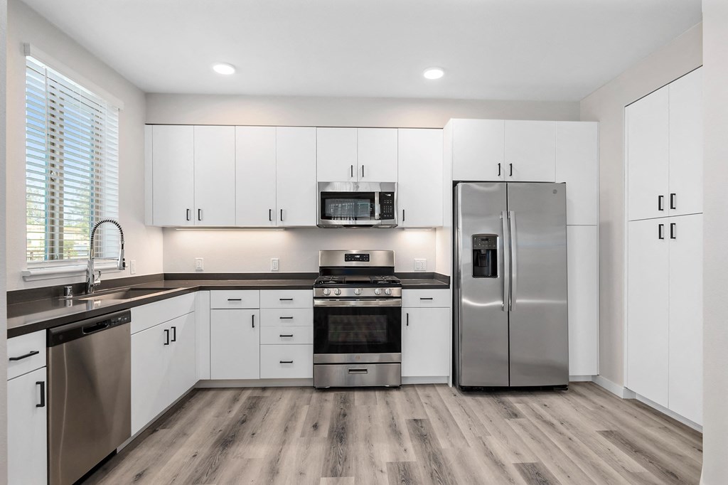 a kitchen with white cabinets and stainless steel appliances at Sierra Gateway Apartments, California
