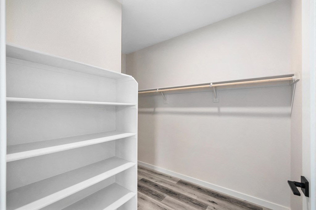 a walk in closet with white shelves and a wood floor at Sierra Gateway Apartments, Rocklin