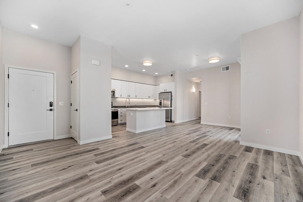an empty living room and kitchen with white walls and wood flooring at Sierra Gateway Apartments, Rocklin, 95677