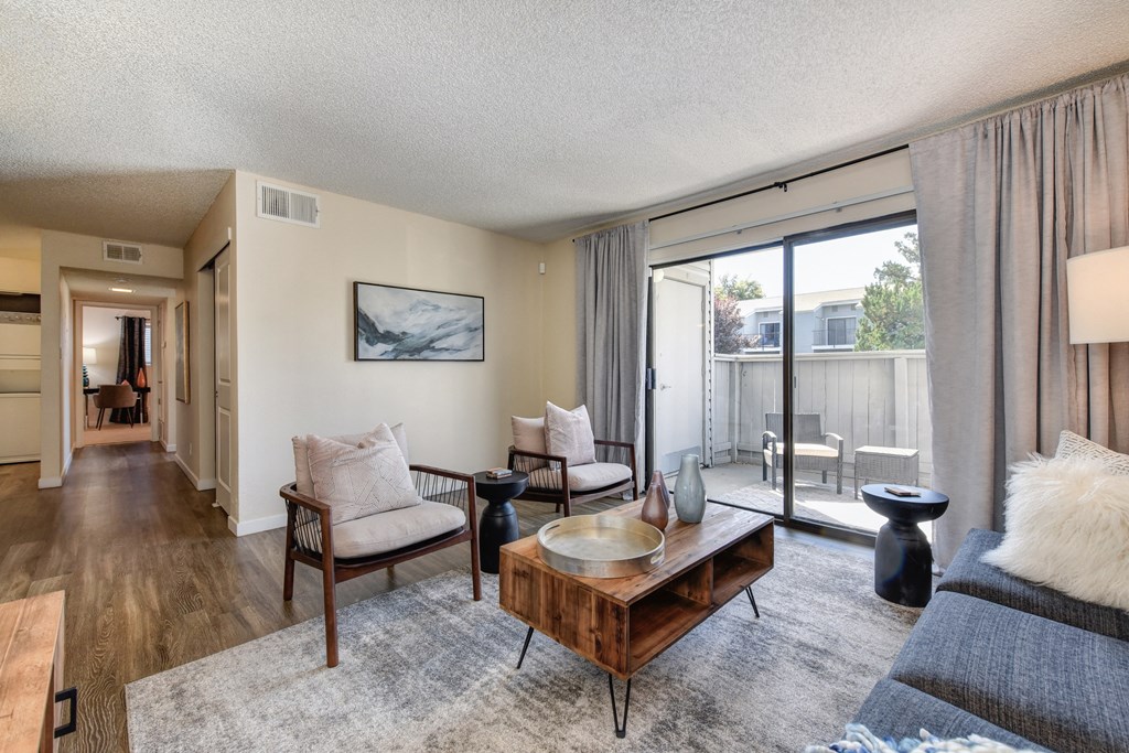 Living with Sliding Patio Doors,  Hardwood Inspired Floor, Gray/White Rug, Gray Sofa and Round Mirror at Silverstone Apartments, California, 95618