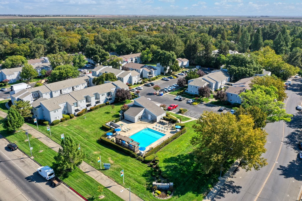 Drone photo overlooking the entire apartment community showcasing the pool, leasing office, mature landscaping and all of the apartment buildings. at Silverstone Apartments, Davis, California