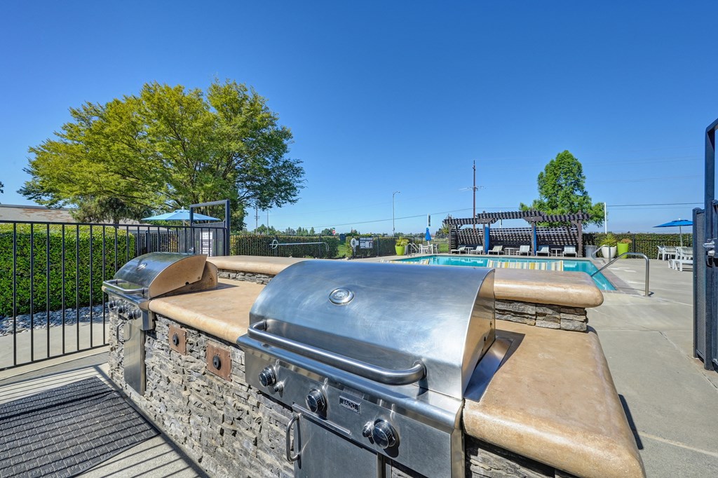BBQ Picnic Area with Grills and View of Lounge Chairs and Pool at Silverstone Apartments, Davis, California