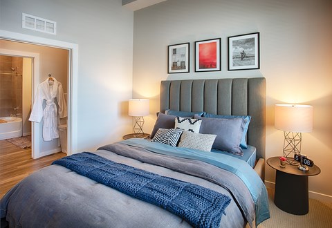 A bedroom with a large bed and a white robe hanging in the doorway.