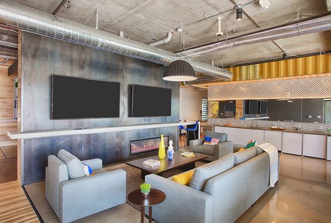 A modern living room with a grey couch and a television mounted on the wall.