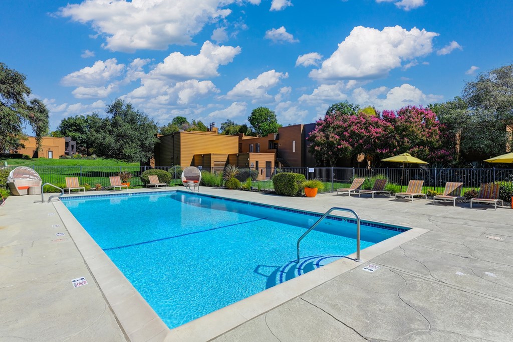 Pool Area with lounge cabana-like chairs, Yellow Umbrellas, Standard Lounge Chairs, and bright blue Pool on a clear day at Fountains of Fair Oaks, Fair Oaks, 95628