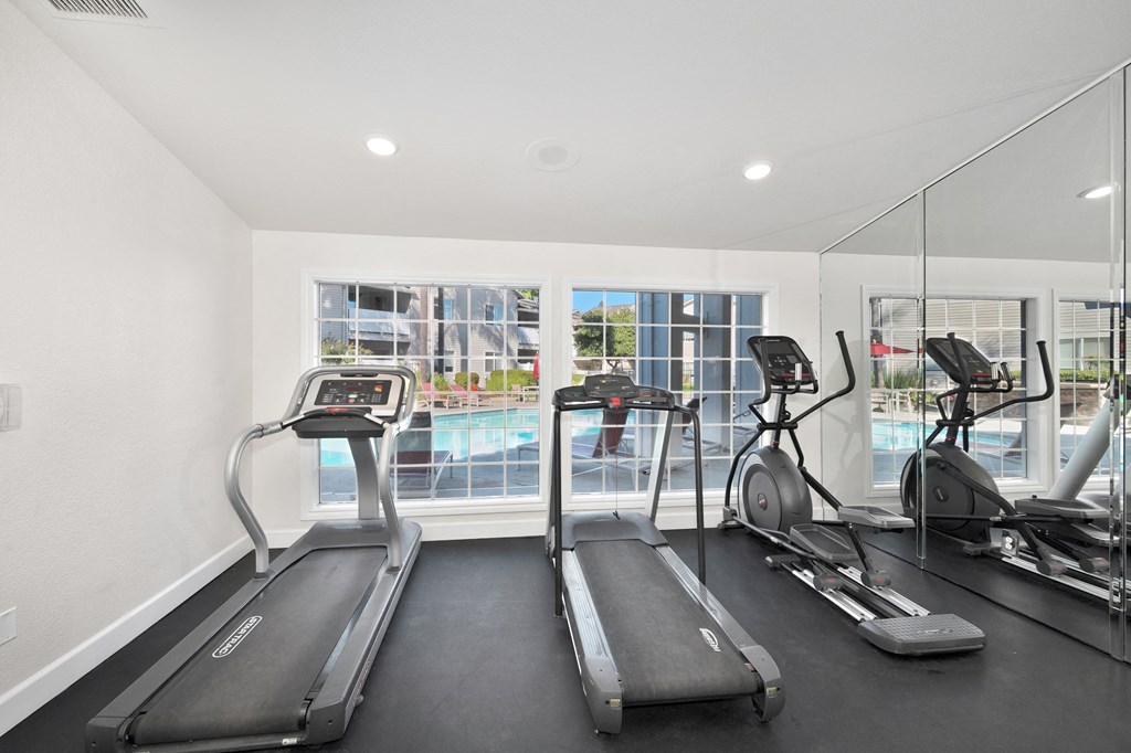 the gym is equipped with cardio equipment and views of the pool at The Legacy Apartments, Antelope, CA, 95843