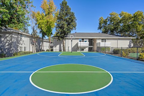 A basketball court is surrounded by apartment buildings.
