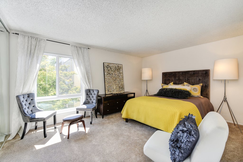 a bedroom with a large window and yellow bedspread