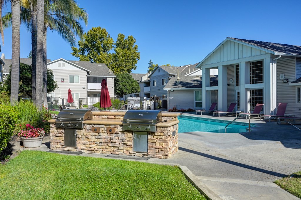 The Legacy Apartments pool area with two built-in gas barbecue grills facing the pool and backside of the clubhouse at The Legacy Apartments, California, 95843