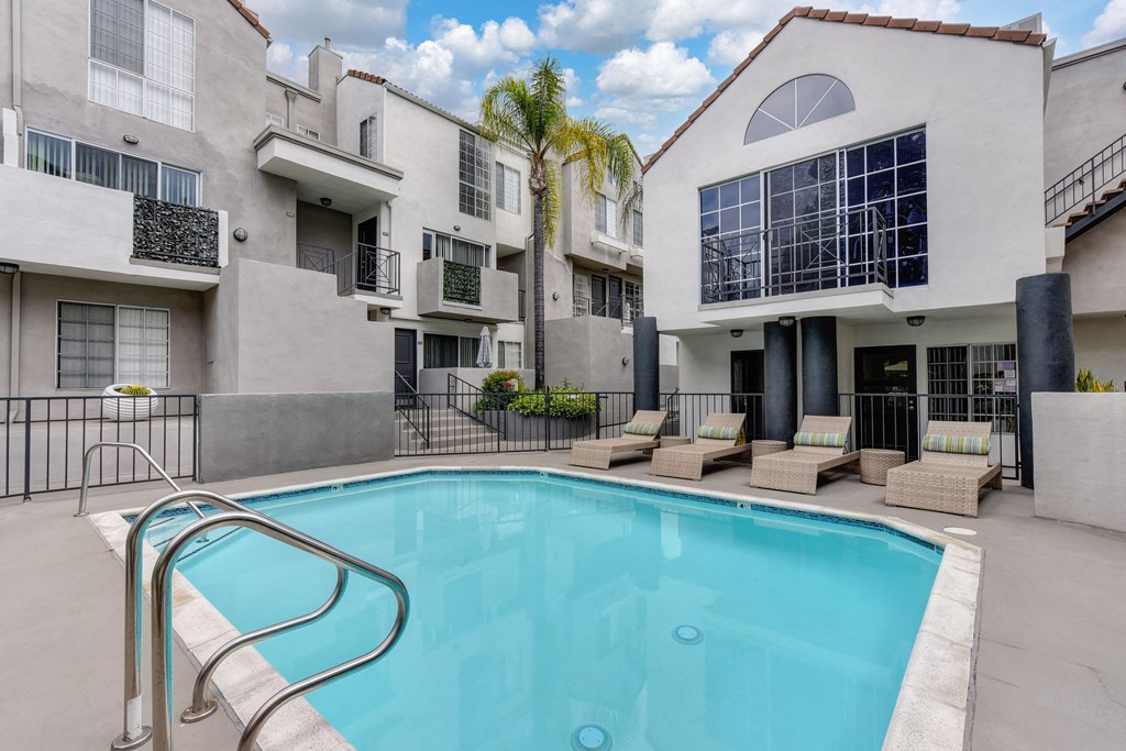 Pool with Lounge Chairs, palm trees and apartment building exteriors