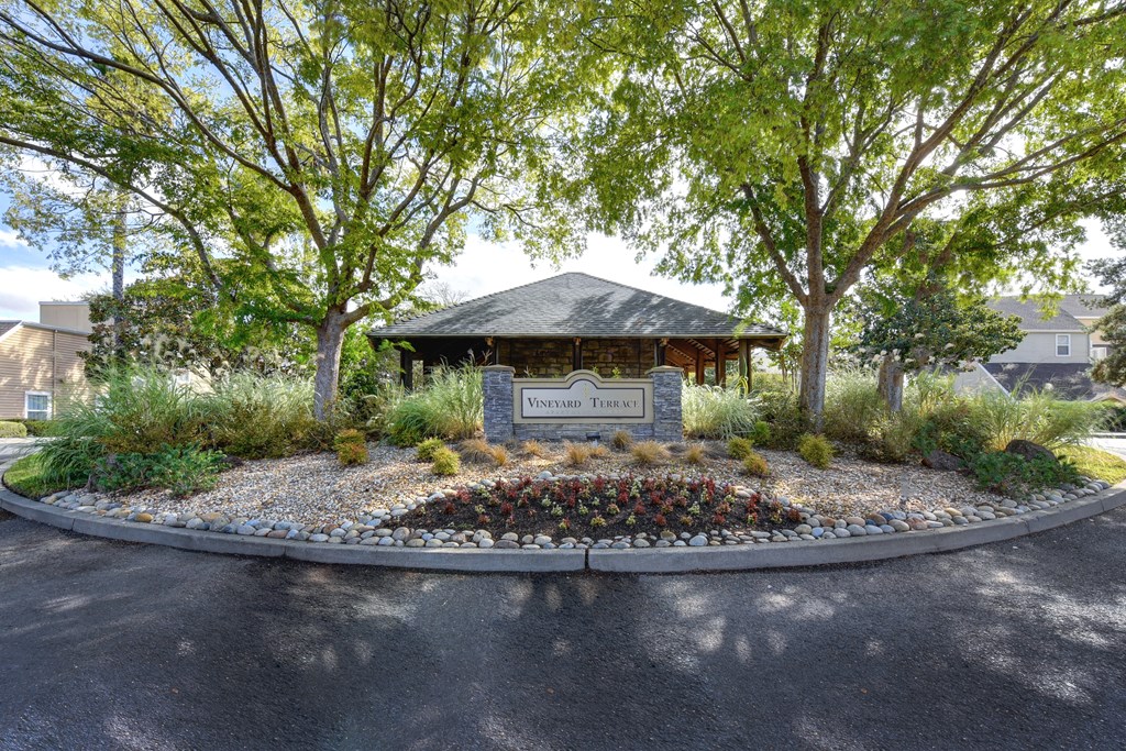 Vineyard Terrace community entrance with monument signage and mature trees on each side at Vineyard Terrace Apartments, Napa, California