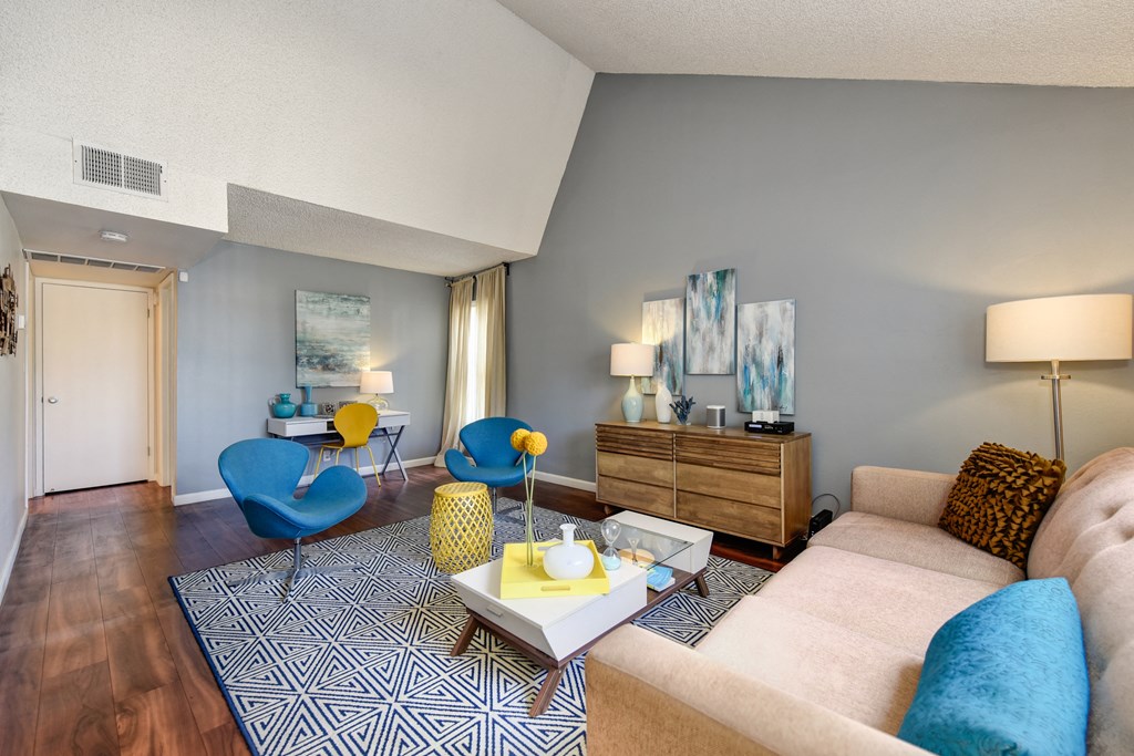 Model home with vaulted ceilings, hardwood inspired flooring and blue accents with the chairs and couch pillows at Vineyard Terrace Apartments, California 94558