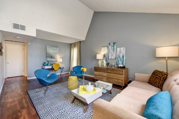 Model home with vaulted ceilings, hardwood inspired flooring and blue accents with the chairs and couch pillows. - Photo Gallery 3