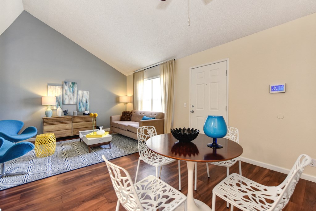 Living Room with View of Kitchen with Hardwood Inspired Floor, White Sofa, Rug and Blue Chairs at Vineyard Terrace Apartments, Napa, California