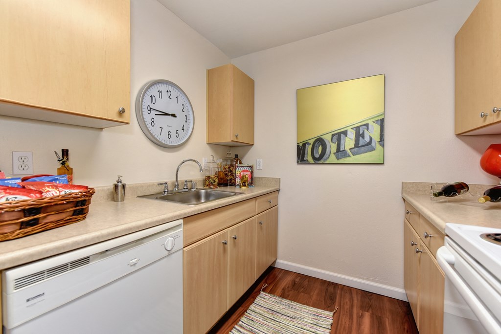kitchen with hardwood inspired flooring, white kitchen appliances, and cabinetry at Vineyard Terrace Apartments, California 94558