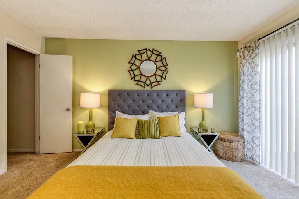 Bedroom with Carpet, light green accent Wall, two nightstands and yellow throw blanket on the bed at Vineyard Terrace Apartments, Napa