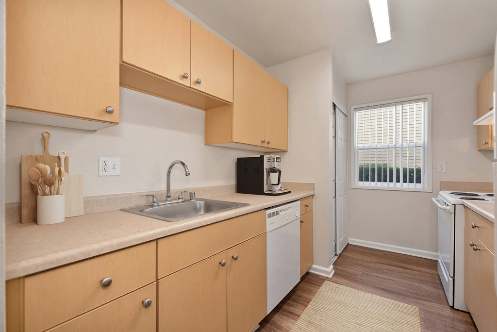a kitchen with wooden cabinets and a sink and a window a kitchen with wooden cabinets and a sink and a window at Vineyard Terrace Apartments, California, 94558