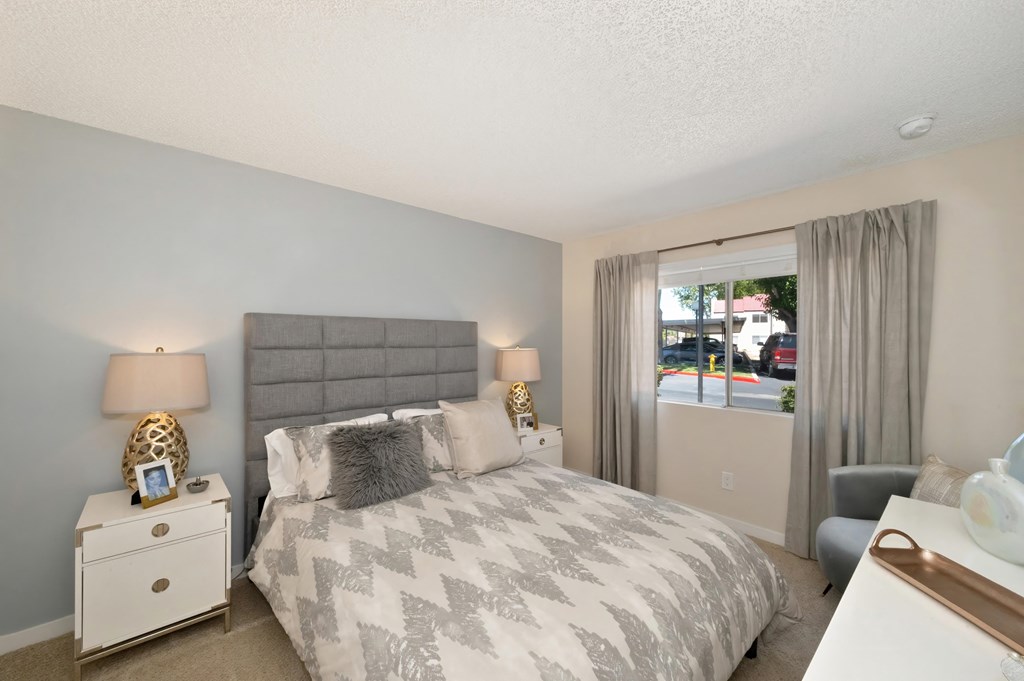 Bedroom with Mattress with Gray/White Comforter, Carpet, White Bedside Dresser with Lamp and Windows