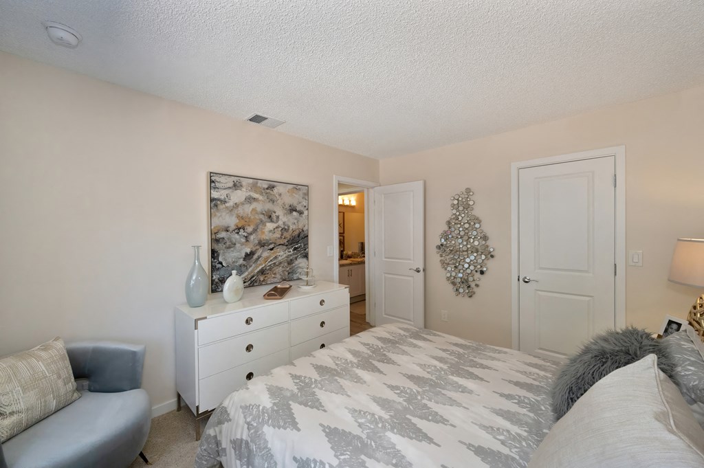 a bedroom with a bed and a dresser and a door to a bathroom