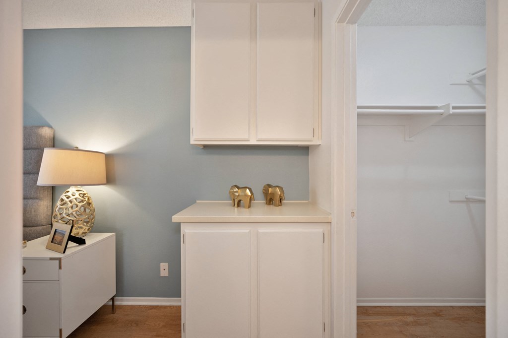a living room with white cabinets and a desk with two gold elephants