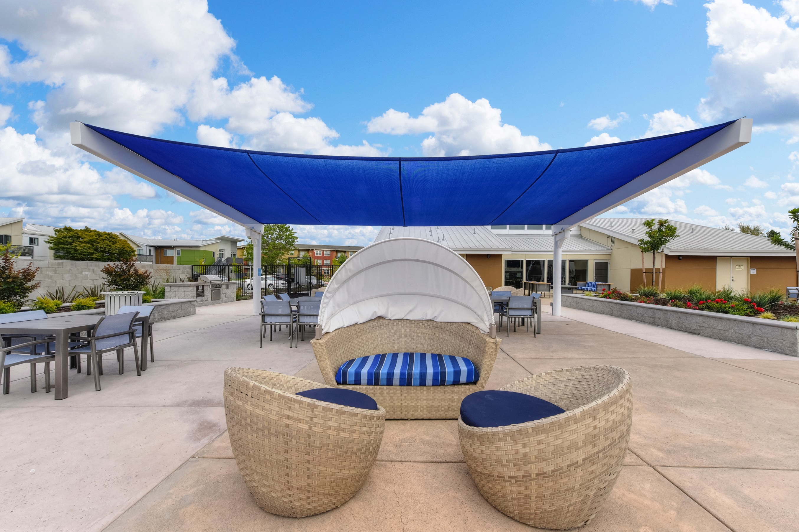 Outdoor Lounge with Wicker Chair, Blue Sun Cover, Tables and Chairs, Blue Sky with Clouds at Addison Ranch Apartments, Petaluma, California