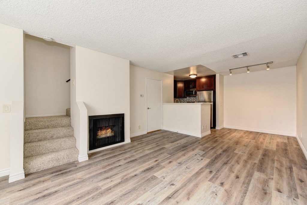 Townhouse floor plan with hardwood inspired flooring, fireplace downstairs and about 5 stairs leading up to the main staircase to the 2nd floor. 