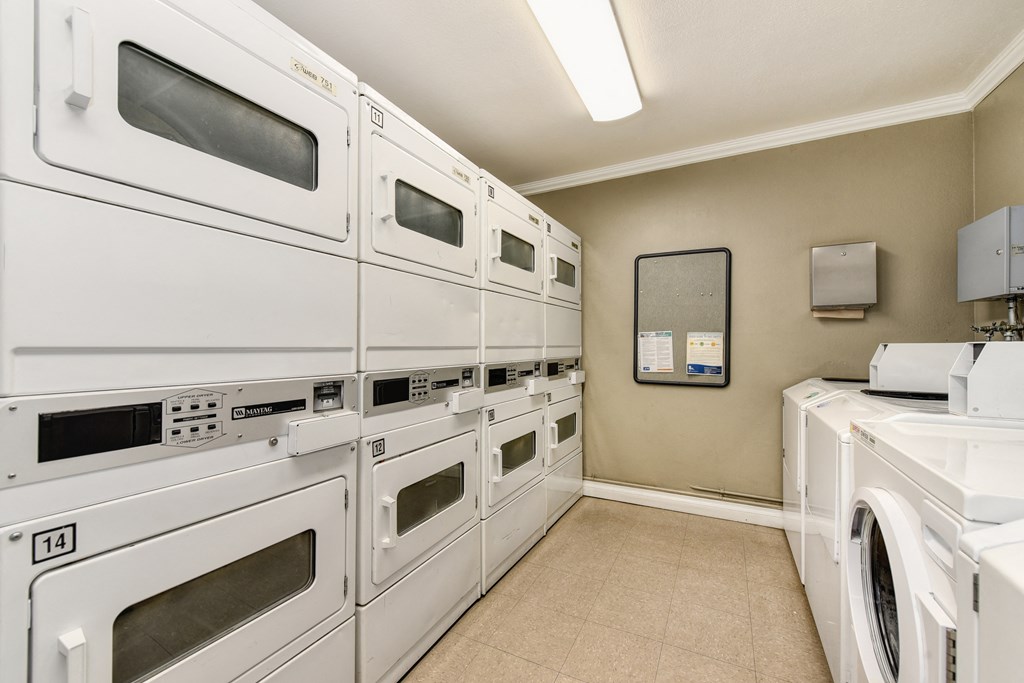 The Woods community laundry room with many washers and dryers in shared access room.
